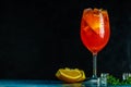 Cocktail aperol spritz in big wine glass with water drops on dark background. Summer alcohol cocktail with orange slices. Italian