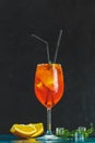 Cocktail aperol spritz in big wine glass with water drops on dark background. Summer alcohol cocktail with orange slices