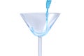 Cocktail with blue liquid in glass. Glass with blue water pouring with liquid with splashes and drops. Martini glass filling with Royalty Free Stock Photo