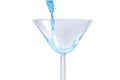 Cocktail with blue liquid in glass. Glass with blue water pouring with liquid with splashes and drops. Martini glass filling with Royalty Free Stock Photo