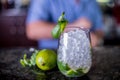 Cocktail decorated with mint and a slice of lime, grass with ice in a glass of wine Balon with bartender on background Royalty Free Stock Photo