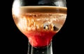 Close up of a balloon cup containing a cocktail based on cream, liqueur and grenadine called Brain Hemorrhage prepared for the Hal