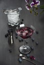 Cocktail in a glass, blueberry fruit, orchid flower, ice bucket, dark gray background. Select focus