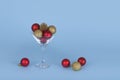 Cocktail glass with Christmas bauble balls on blue background. Creative Xmas or New year celebration concept Royalty Free Stock Photo