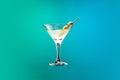 Cocktail glass with dry martini with olives isolated over gradient blue green color background in neon. Royalty Free Stock Photo