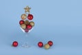 Cocktail glass with flying Christmas bauble balls on blue background. Minimal Christmas party idea Royalty Free Stock Photo