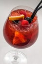 Cocktail in a glass goblet with orange, raspberry and blackberry