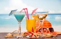 Cocktail, glass of juice and alcohol with olives, hat, sunglasses, starfish, seashells and twine on background of sea. Royalty Free Stock Photo
