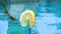 Cocktail glass with lemon slice, rosemary near swimming pool. Vacation, summer Royalty Free Stock Photo