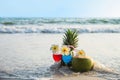 Cocktail glasses with coconut and pineapple on clean sand beach