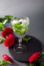 Cocktail with ice cubes and peppermint set with red roses