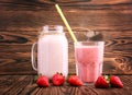 Cocktail in a mason jar and a glass with a straw and a lot of sweet berries around on a wooden background. Strawberry smoothie Royalty Free Stock Photo