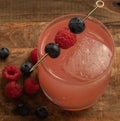 Overview cocktail mixed glass with blueberry and a raspberry with a wooden background Royalty Free Stock Photo