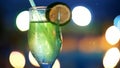 cocktail party, drink with ice, in a glass with a straw and decorated with a slice of lemon, in the rays of soffits Royalty Free Stock Photo