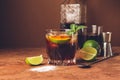 Cocktail of rum and cola ice cubes and lime in a glass goblet on a dark brown background. Strong alcoholic drink.