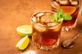 Cocktail of rum and cola ice cubes and lime in a glass goblet on a dark brown background. Strong alcoholic drink.