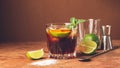 Cocktail of rum and cola ice cubes and lime in a glass goblet on a dark brown background. Strong alcoholic drink.