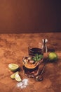 Cocktail of rum and cola ice cubes and lime in a glass goblet on a dark brown background. Strong alcoholic drink.