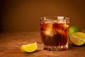 Cocktail from rum ice cubes and lime in glass goblet on a dark brown background. Strong alcoholic drink. Copy space.