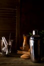 Cocktail shaker, swizzle, tongs and spoon with ice in a bucket for preparing a summer cocktail beverage on a black table