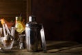 Cocktail shaker, swizzle, tongs and spoon with ice in a bucket for preparing a summer cocktail on dark background with