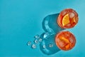 Cocktail. Two glasses with cool beverages, sliced oranges and ice on blue background with shadow. Top view with copy space Royalty Free Stock Photo