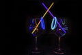 Cocktail wine glass filled with exotic illuminated refreshing juicy liquid and colorful straw with black background for nightlife