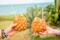 Cocktails in pineapple with straw in hands against the sea in Varadero, Cuba. Vacation concept