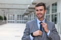 Cocky businessman adjusting his tie with copy space