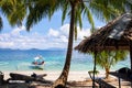 Coco palm tree and white beach on sunny day. Tropical island paradise photo. Rustic hut and traditional boat Royalty Free Stock Photo