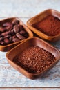 Cocoa beans, powder and grated chocolate in wooden bowls Royalty Free Stock Photo