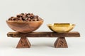 Cocoa beans in a wooden bowl and golden spoon on a wooden stand isolated on white background