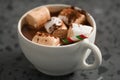 Cocoa drink with marshmallow and christmas drinking straw in white cup on terrazzo surface closeup