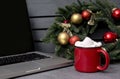 Cocoa, hot chocolate and marshmallows next to the laptop, spruce Christmas wreath with  balls on a gray background, side view Royalty Free Stock Photo