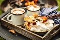 Cocoa or hot chocolate and skewers of roasted marshmallows over campfire