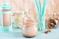 Cocoa in a jar. In the background, a turquoise coffee pot, marshmallows and blue cocktail tubes in a blur. A gentle