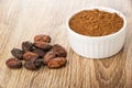 Cocoa powder in bowl, unpeeled cocoa beans on table