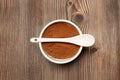 Cocoa powder in a white bowl with a white spoon on it and on a wooden background Royalty Free Stock Photo