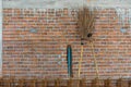 Coconut broom and steel bar near new interior red brick wall under construction background