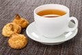 Coconut cookies, cup with tea on saucer on dark mat