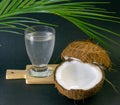 Coconut exotic fruit, two coconut halves in the shell, dark background, a glass of coconut water on the kitchen and blackboard,