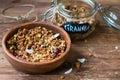 Coconut granola in wooden bowl and glass jar on wooden background