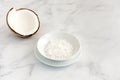 Coconut Half and Grated Coconut in a Bowl on White Marble Royalty Free Stock Photo