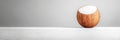 Coconut Half on White Surface A half coconut shell with white coconut milk inside sits on a white surface against a gray Royalty Free Stock Photo