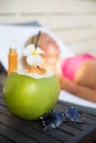 Coconut juice drink with woman on lounger near a swimming pool