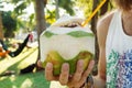 Coconut with juice and orange straw in a hand of man on a background of park with palm trees. Royalty Free Stock Photo