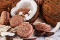 Coconut macarons with chocolate and coconut flakes on a table with a coconut in the background