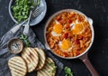 Coconut milk curry vegetables shakshuka and grilled bread on dark background, top view