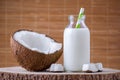 Coconut milk in glass bottle with tubule on natural brown background