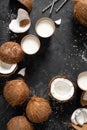 Coconut milk, whole and cracked coconuts on black background Royalty Free Stock Photo